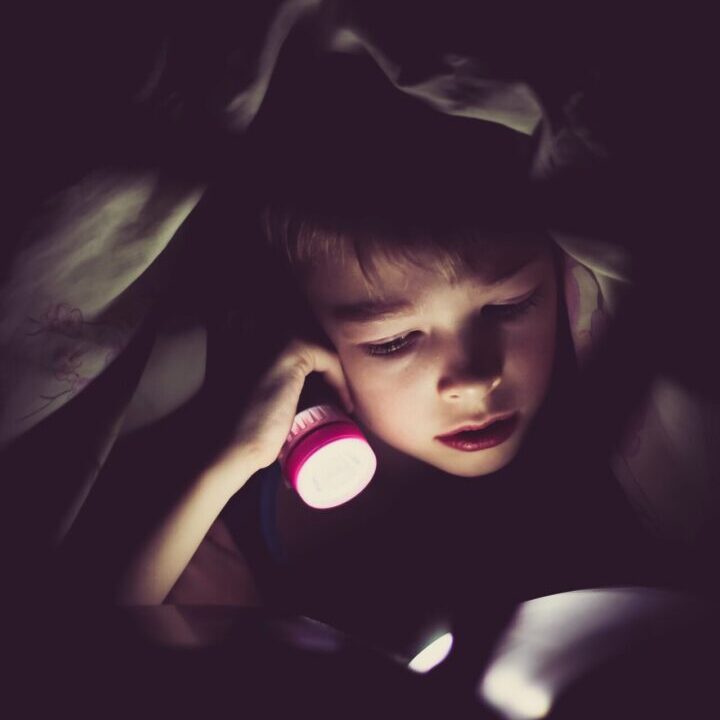 a child holding a lit flashlight
