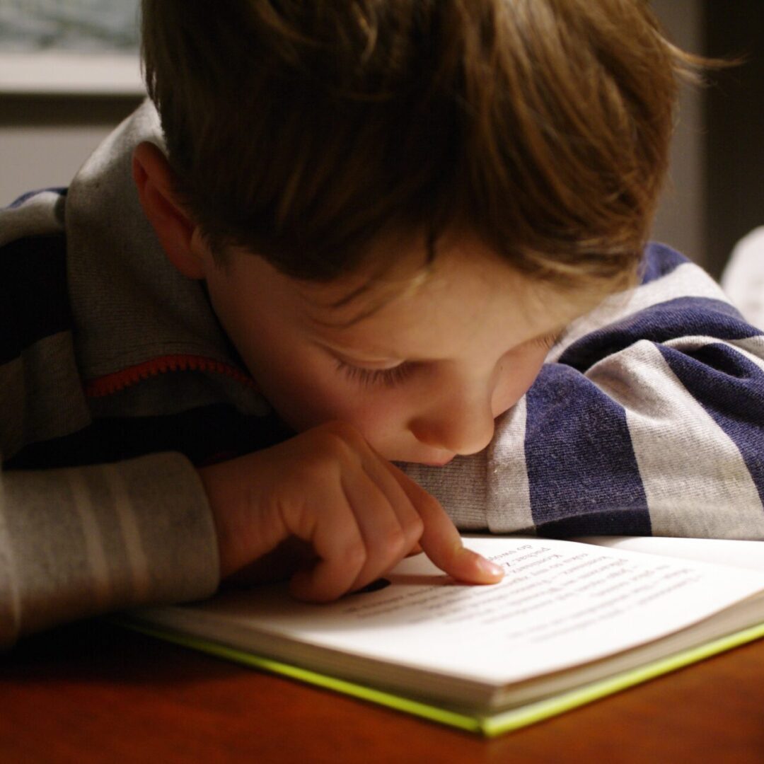 a boy reading a book on a table