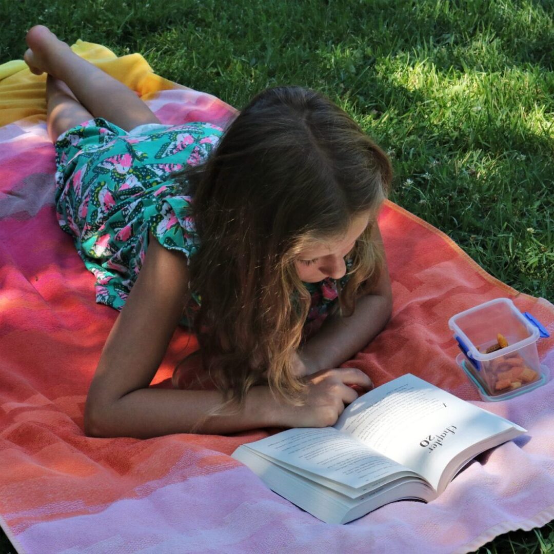 a girl reading a book on a beach towel